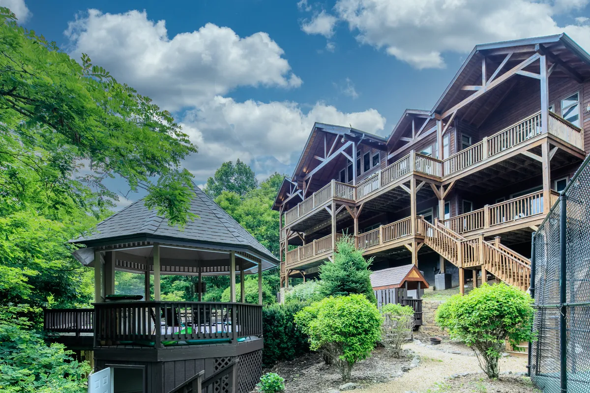 This exterior view captures a charming wooden gazebo nestled among greenery, set in front of the multi-level lodge. The picture evokes a peaceful mood, ideal for group gatherings, morning coffee, or evening barbecues, and features lush grounds for exploration.