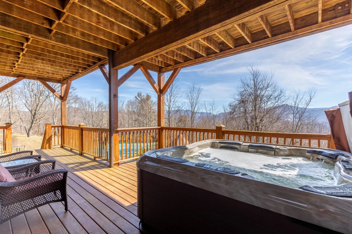 A serene hot tub set on a wooden deck overlooking expansive mountain views. The setting is tranquil, perfect for unwinding after a day exploring local towns, ski slopes, or trails. The positioning of the hot tub and view reflects the seamless integration of home comfort with outdoor adventure.