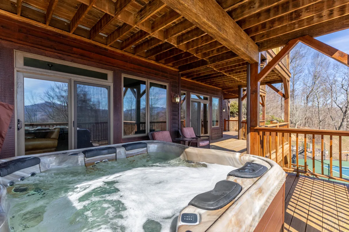 A tranquil outdoor setup featuring a steaming hot tub, comfortable seating, and sturdy wooden beams, all oriented toward a stunning mountain backdrop. This setting invites guests to soak, sip morning coffee, or gaze at the stars, offering a peaceful retreat that blends luxury with nature.