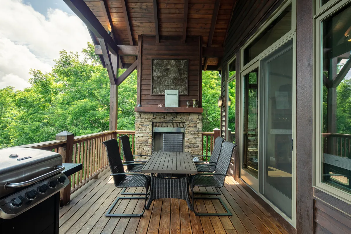 A spacious outdoor dining area complete with a wooden deck, fireplace, grill, and surrounded by lush greenery. The scene is set for gathering with friends or family, echoing the convivial spirit of the region's food, festivals, and community events.